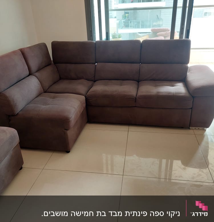 ספה חומה על רצפה מבריקה ליד חלון גדול